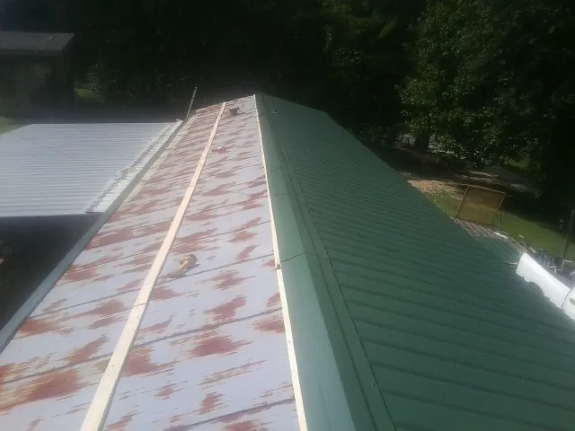 Old rusted panels beside newly installed green metal roofing — Wind Damage Roof Repair by Roofing Brothers in Chiefland