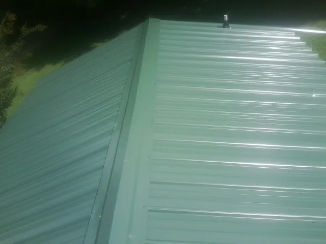 New green metal panels meeting at the ridge of a roof — Flat Roof Repair work by our crew in Chiefland