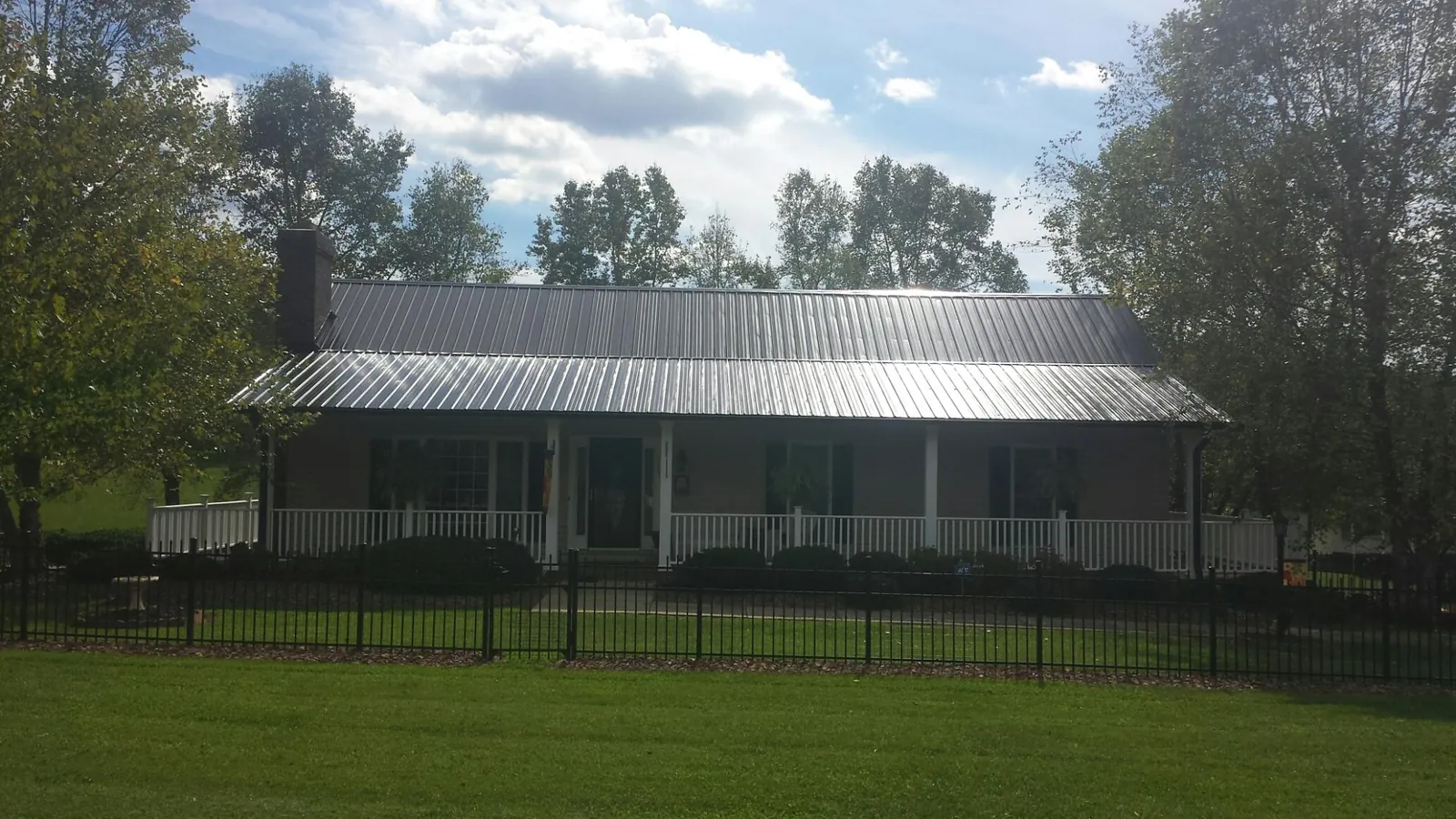 Gray metal roof on a brick ranch with a full width front porch — Gutter Guard Installation work by our crew in Chiefland