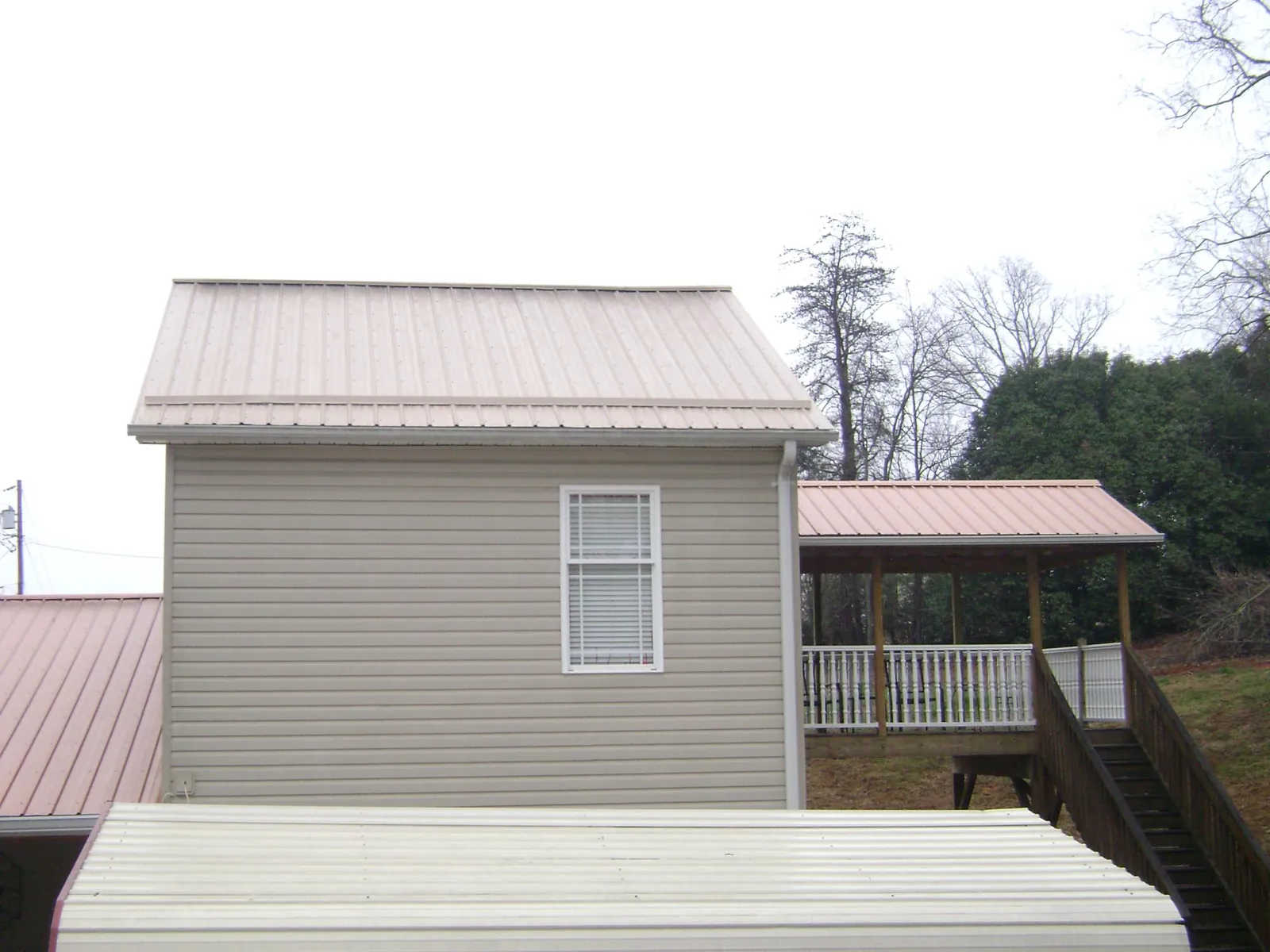 Tan metal roofs on a two story addition and attached porch, from a Roof Replacement job in Chiefland